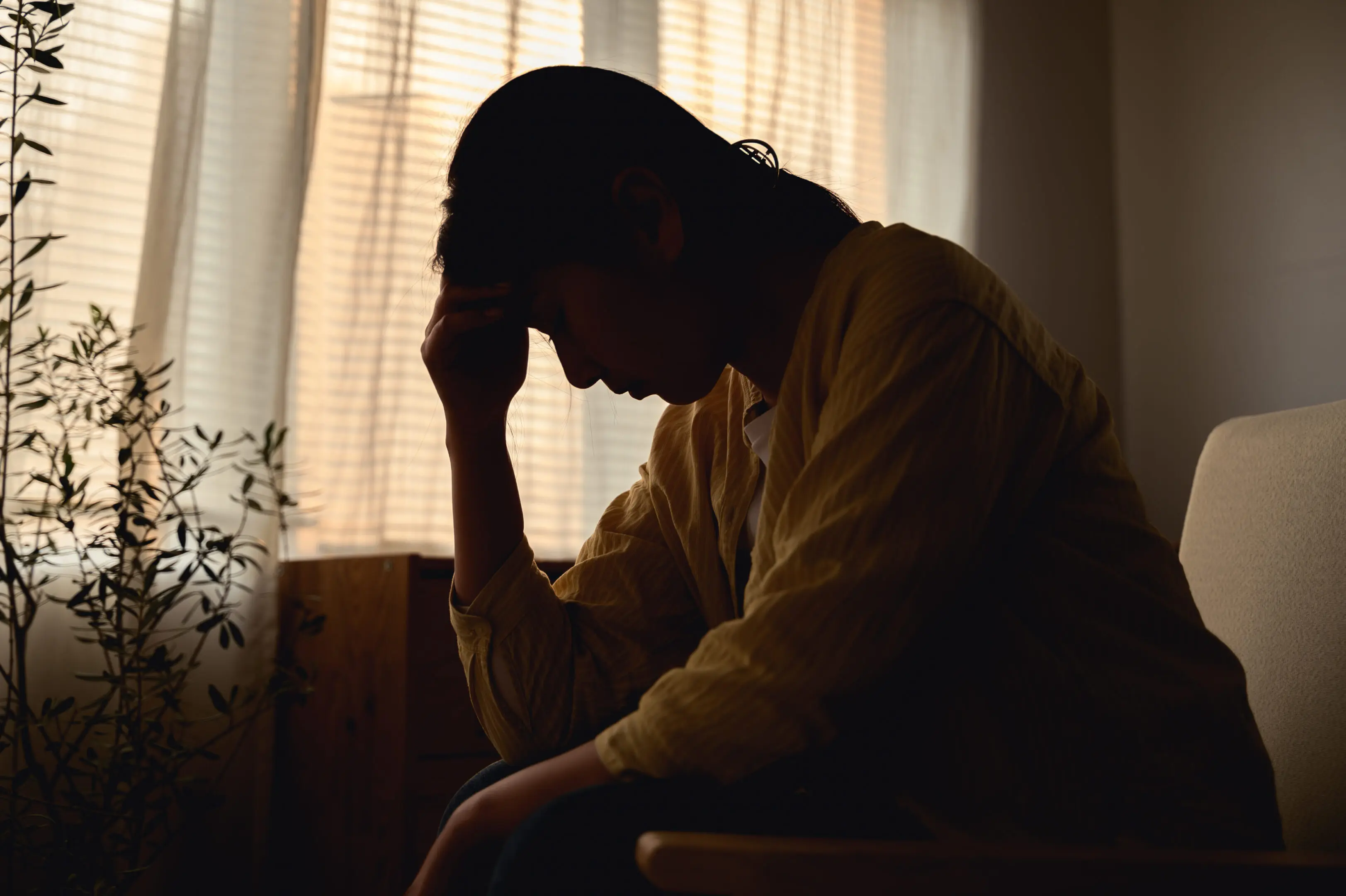 Silhouette photo of young Asian woman feeling upset, sad, unhappy or disappoint crying lonely in her room. Young people mental health care problem lifestyle concept.